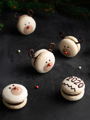 Macaron red nose reindeer and macaron with 2020 number with fir tree brances on dark black...