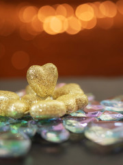 Golden hearts with glitter on a glass snowflake, Saint Valentine theme. Blurred warm bokeh background.