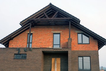 facade of a private house of red and brown bricks in the wall with windows against the sky