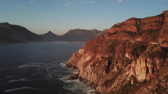 4K high quality aerial sunny afternoon sunset footage of spectacular scenic Chapman's Peak Drive, rocky mountains, Atlantic Ocean between Hout Bay, Noordhoek in Western Cape, Cape Town, South Africa