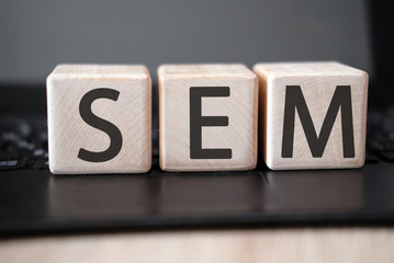 SEM text on wooden cubes on a monochrome background with reflection.