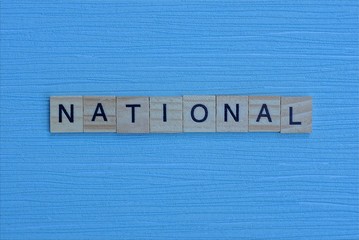 gray word national from small wooden letters on a blue table