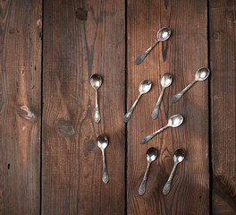 set of small metal teaspoons on a brown wooden table, top view