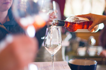 close up of hand pouring wine into wine glasses at wine tasting