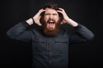 Photo of angry bearded man screaming over dark background