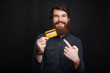 Happy bearded man pointing at his new yellow credit card