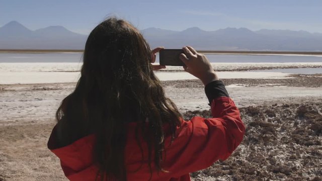 Woman in red vest taking picture with her cell phone in Laguna Cejar, Chile, Atacama