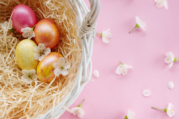 Easter basket with golden easter eggs on pink background.