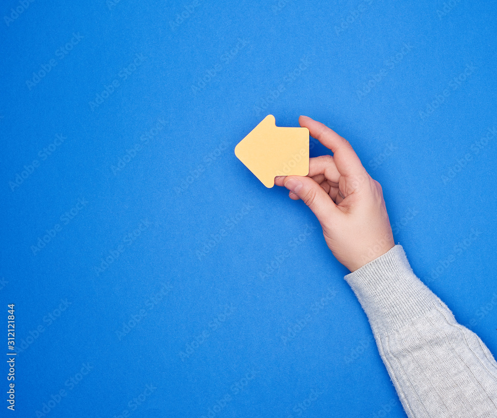 Poster hand holds an orange paper sticker in the form of an arrow pointer