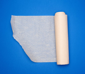 roll of brown parchment paper on a blue background, copy space