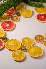 Fototapeta na wymiar Creative holiday Christmas New Year food fruit texture with dried grapefruit, kiwi, orange and lemon with branch of fir tree, angle view, empty white background copy space