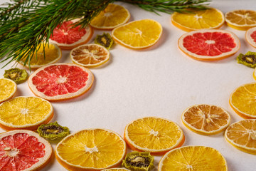 Fototapeta na wymiar Creative holiday Christmas New Year food fruit texture with dried grapefruit, kiwi, orange and lemon with branch of fir tree, angle view, empty white background copy space
