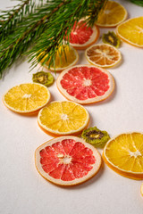 Creative holiday Christmas New Year food fruit texture with dried grapefruit, kiwi, orange and lemon with branch of fir tree, angle view, white background, macro and selective focus