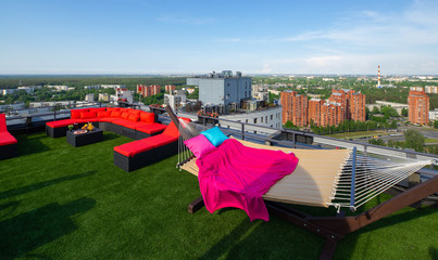 Cozy red couch and hammock on the rooftop terrace. Sunny summer day.