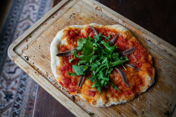 Homemade rustic anchovy arugula pizza 