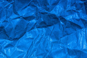 A close up abstract macro photo of crumpled creased paper lit with a blue flash gel
