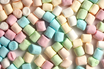 Many colorful mini marshmallows for coffee and cacao decoration laying flat on tje white background. Food close up.