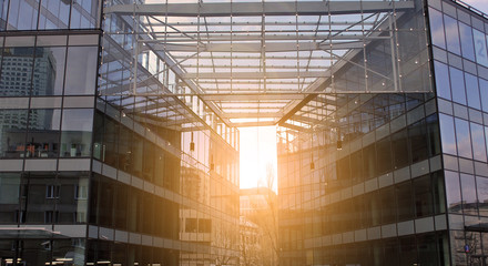 Sun rays light effects on urban buildings in sunset. Modern office building detail, glass surface with sunlight. Business background. 