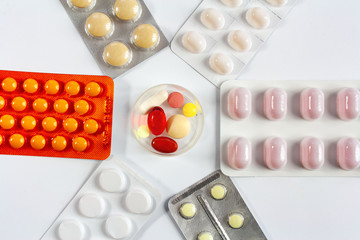 Tablets in a plastic container surrounded by tablets in packaging