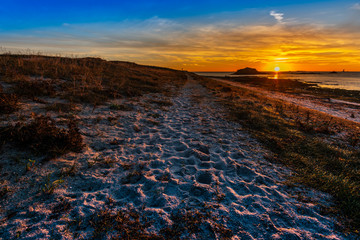 The walk pass along the sandy coast facing to the sunrise in South of Hoedic Island in French Brittany.