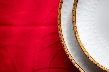 white porcelain dish with golden relief with decorations on a red table. luxury plates and dishes used for celebrations. porcelain plate and setting up the dinner table in red. Christmas party