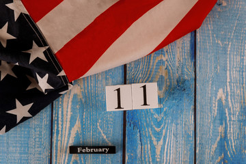 11 February calendar beautifully waving star and striped American flag on old wooden board.