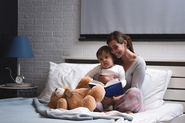 Mother playing with her baby in the bedroom.