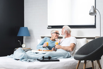 Senior couple having breakfast in bed together - Powered by Adobe