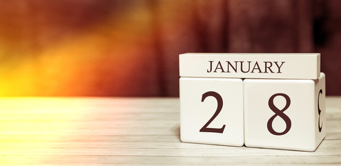 Calendar reminder event concept. Wooden cubes with numbers and month on January 28 with sunlight.
