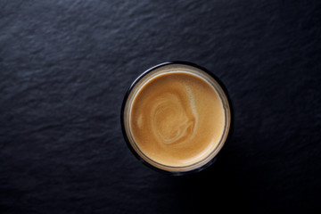 Coffee in glass cup on dark stone background. Top view. Copy space. 