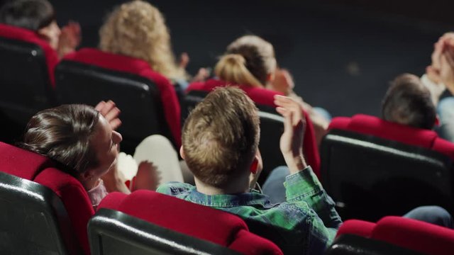 From above view of satisfied audience applauding after watching movie in cinema. Middle aged couple talking cheerfully and discussing happy ending