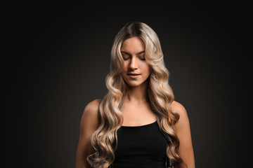 Naklejka premium Beautiful young woman with curly hair on dark background