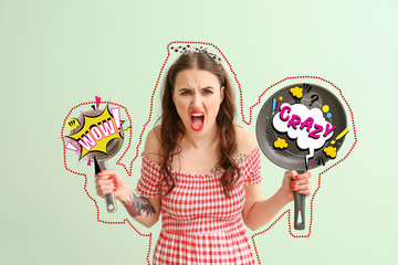 Funny angry housewife with kitchenware on color background