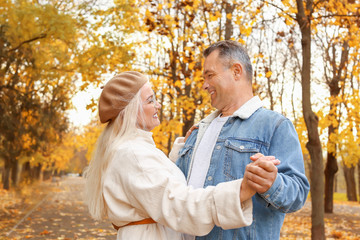 Happy mature couple dancing in autumn park