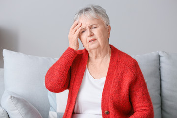 Senior woman suffering from headache at home