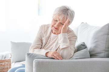 Senior woman suffering from headache at home