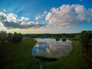 Fototapeta premium Large pond, barns, blue sky and green grass as seen from an aerial drone