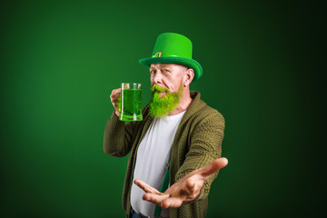Funny mature man with glass of beer inviting viewer on dark background. St. Patrick's Day celebration