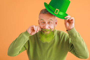 Funny mature man on color background. St. Patrick's Day celebration
