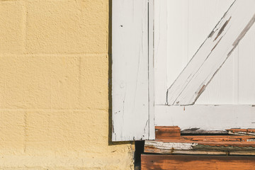 Distressed white barn style door  yellow concrete background texture