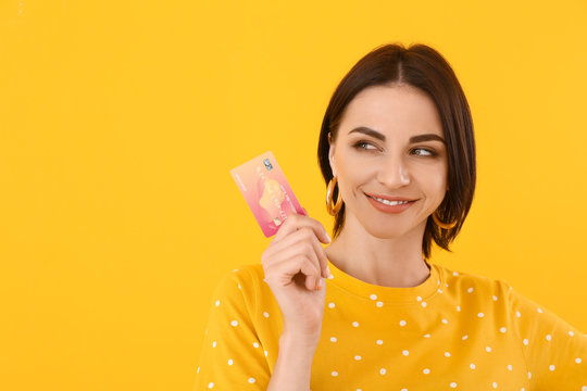 Beautiful young woman with credit card on color background