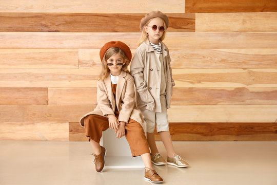 Cute little girls in autumn clothes near wooden wall