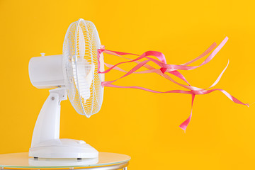 Electric fan with fluttering ribbons on color background - obrazy, fototapety, plakaty
