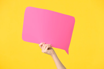 Female hand with blank speech bubble on color background