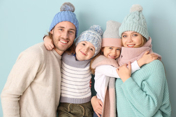 Happy family in winter clothes on color background