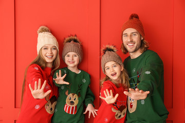 Happy family in Christmas clothes on color background