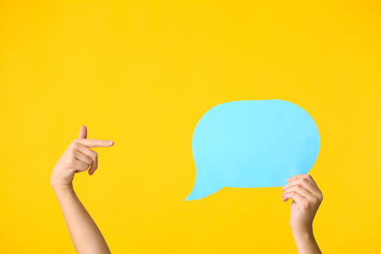 Female hands and blank speech bubble on color background