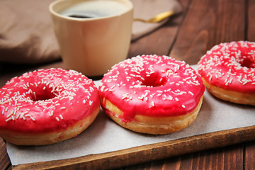 Sweet tasty donuts and cup of coffee on wooden background