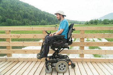 disabled Young man in electric wheelchair on a boardwalk enjoying his freedom and observing nature