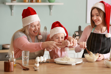 Young woman with her little daughter and mother cooking Christmas cookies at home